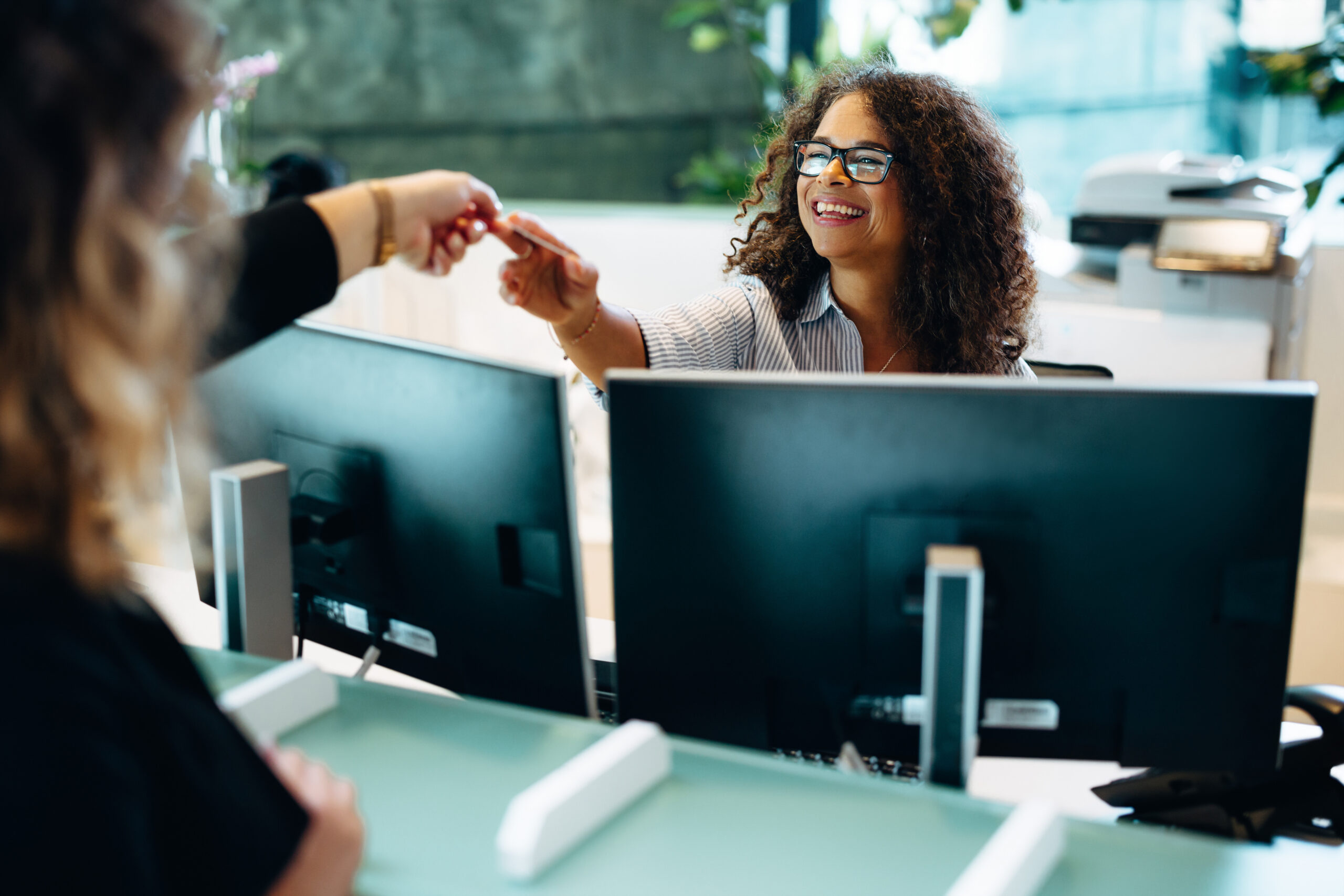 Female receptionist giving back the card to the woman at front desk